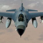 Powerful fighter jet soaring through clouds with visible missiles.