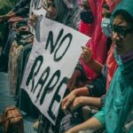 Group of women holding signs protesting against rape, highlighting social issues and activism.