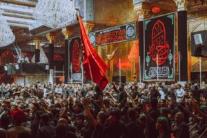 A large crowd participates in a religious ceremony at a notable landmark in Karbala, Iraq.