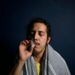Close-up of a young man comfortably smoking in a dimly lit room, reflecting relaxation.